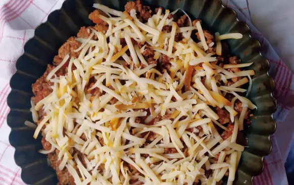 Na pánvi si orestujeme obě mletá masa, osolíme a okořeníme. Přidáme nakrájená pasterizovaná rajčata (lze použít i čerstvá, ale je zapotřebí je spařit a oloupat). Pod pokličkou necháme dusit asi 30 minut. Občas promícháme. Že máme hotovo poznáme podle toho, že se nám zredukuje tekutina a zůstane nám hustá směs. 
Mezitím, co nám směs probublává, nakrájíme si celer a mrkev na kostičky a v osolené vodě vaříme do měkka. Poté scedíme a za postupného přilévání smetany vyšleháme do hustějšího pyré. 
Do koláčové formy dáme nejdříve směs z mletého masa, poté posypeme nastrouhaným sýrem a nakonec pokryjeme celerovo-mrkvový pyré. Pečeme v předem vyhřáté troubě na 180°C 40-45 minut.