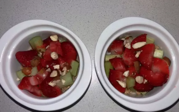 Do mísy dejte vločky, mouku, máslo a med a prsty propracujte drobenku. 
Část dejte do vymazaného pekáčku či zapékacích misek.
Na drobenku položte na kousky nakrájenou rebarboru a jahody, posypte nahrubo nakrájenými mandlemi a přikryjte zbytkem drobenky.